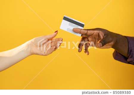 Cashless payment. Banking service. Budget management. Retail shopping. hands buying man customer giving credit card to white woman isolated on orange copy space. Cashless payment. Banking service. Budget management. Retail shopping. hands buying man customer giving credit card to white woman isolated on orange copy space. 85089380