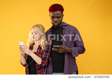 Gadget addiction. Internet dependency. Mobile communication. Modern technology.  serious couple  man  woman using phone app isolated on orange background. 85089399