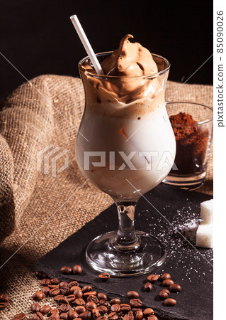 Dalgona coffee cold drink with milk whipped with foam, Korean trend home-made coffee. It stands on a black stone stand 85090026