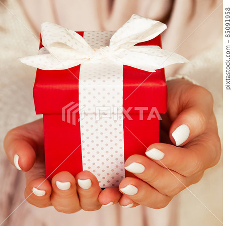 Happy young smiling woman holding and holding red gift box in fr 85091958