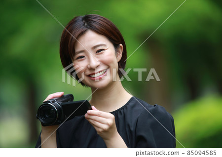 Woman shooting with a video camera 85094585