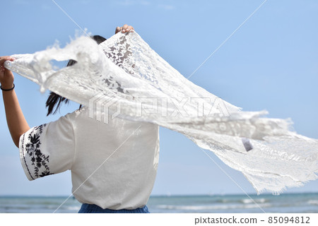 A woman flipping a white lace under the blue sky 85094812