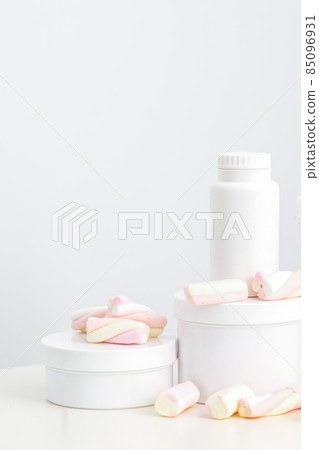Cosmetic skincare packaging. Beauty product on white background. White jars with marshmallows on the white table. Cosmetic skincare packaging. Beauty product on white background. White jars with marshmallows on the white table. 85096931
