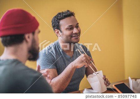 Dark-skinned smiling guy eating thai food Dark-skinned smiling guy eating thai food 85097748