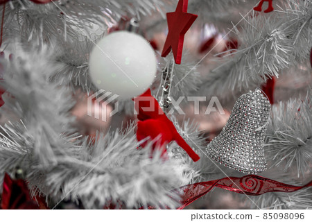 Beautiful Christmas red and silver balls on a white Christmas tree with decorations in the form of ribbons with the inscriptions Merry Christmas and Happy New Year 85098096