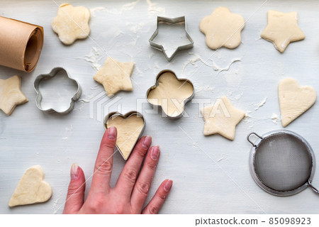 Top view of woman hands cooking a gingerbread cookie in the form of heart, star, cloud and flower. Christmas and New Year concept, festive preparations for winter hilodays Top view of woman hands cooking a gingerbread cookie in the form of heart, star, cloud and flower. Christmas and New Year concept, festive preparations for winter hilodays 85098923