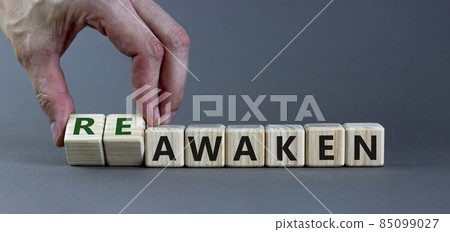Reawaken symbol. Businessman turns cubes and changes the word 'awaken' to 'reawaken'. Beautiful grey background, copy space. Business and reawaken or awaken concept. 85099027