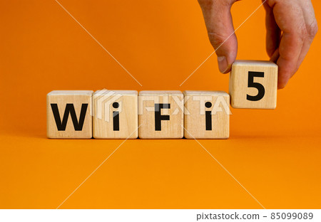 WiFi 5 symbol. Businessman holds a wooden cube with words WiFi 5. Beautiful orange background, copy space. Business, technology and WiFi 5 concept. WiFi 5 symbol. Businessman holds a wooden cube with words WiFi 5. Beautiful orange background, copy space. Business, technology and WiFi 5 concept. 85099089