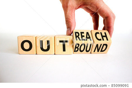 Outreach or outbound symbol. Businessman turns wooden cubes and changes the word 'outbound' to 'outreach'. Beautiful white table, white background. Business, outreach or outbound concept. Copy space. Outreach or outbound symbol. Businessman turns wooden cubes and changes the word 'outbound' to 'outreach'. Beautiful white table, white background. Business, outreach or outbound concept. Copy space. 85099091