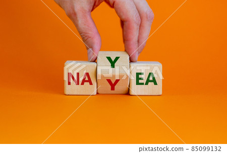 Yea or nay symbol. Businessman turns a cube, changes the word 'nay' to 'yea'. Beautiful orange background. Copy space. Business, motivation and yea or nay concept. 85099132