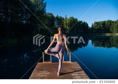 Healthy woman practicing yoga on the lake at sunrise enjoying positive energies from nature Healthy woman practicing yoga on the lake at sunrise enjoying positive energies from nature 85100808