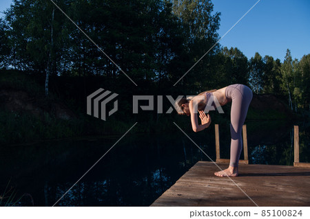 Girl is practicing yoga technique on the pier by the lake and meditating. Meditation to purify mind and calm. Girl is practicing yoga technique on the pier by the lake and meditating. Meditation to purify mind and calm. 85100824