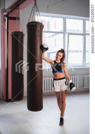 Female athlete boxing the punching bag in urban industrial gym Female athlete boxing the punching bag in urban industrial gym 85100877