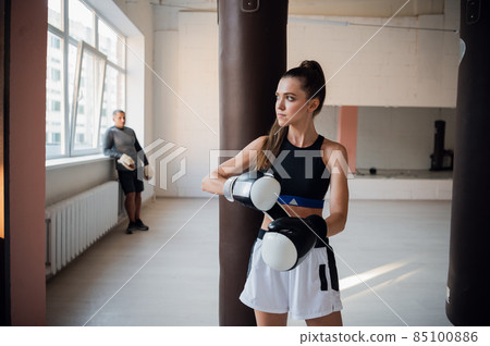 Woman training boxing with personal trainer. Instructor teaching female boxer fighting practice together Woman training boxing with personal trainer. Instructor teaching female boxer fighting practice together 85100886