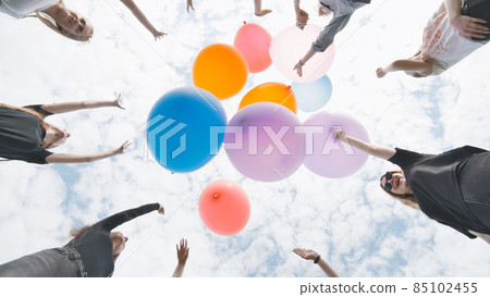 Cheerful girlfriends connect large colorful balls in a circle. Cheerful girlfriends connect large colorful balls in a circle. 85102455