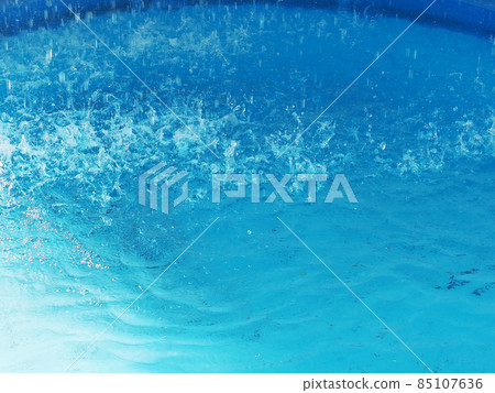 Fragment of a blue pool with splashes of water from a pouring fountain. Closeup photo Fragment of a blue pool with splashes of water from a pouring fountain. Closeup photo 85107636
