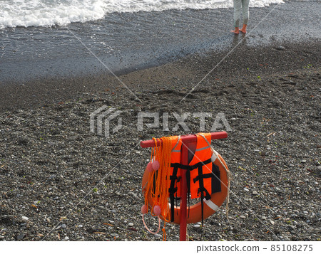 Orange rescue equipment hangs on the pebble beach of the foamy sea 85108275