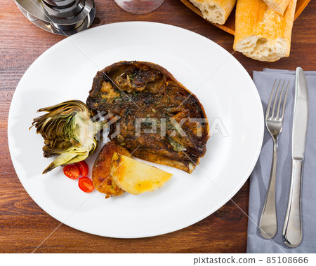 Cabeza de cordero - spanish dish. Lamb head with artichoke, tomatoes and potatoes 85108666