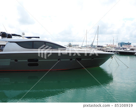 Luxury gray yacht moored in turquoise sea water in the port against the backdrop of other yachts and cloudy sky Luxury gray yacht moored in turquoise sea water in the port against the backdrop of other yachts and cloudy sky 85108919