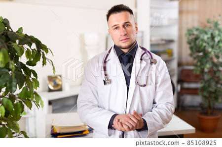 Portrait of friendly male doctor in white coat at clinic Portrait of friendly male doctor in white coat at clinic 85108925