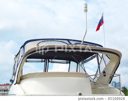 The upper part of the yacht with the tricolor Russian flag against the blue sky with clouds 85108926