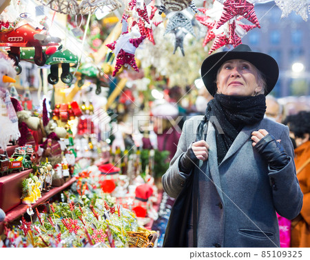 Smiling aged woman walking at traditional city christmas fair Smiling aged woman walking at traditional city christmas fair 85109325