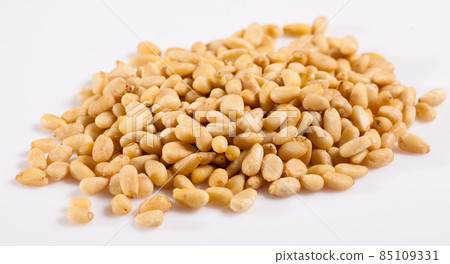 Pile of delicious pine nuts on a white surface Pile of delicious pine nuts on a white surface 85109331
