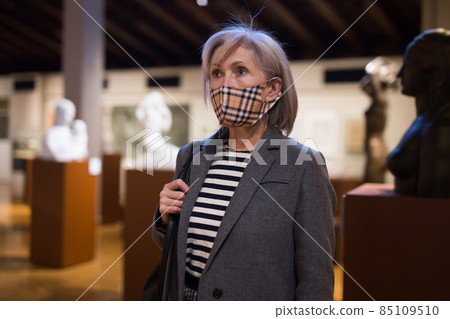 Interested woman in protective mask exploring artworks in museum Interested woman in protective mask exploring artworks in museum 85109510