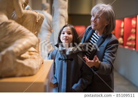 Elderly female tutor showing tween girl ancient sculptures in museum Elderly female tutor showing tween girl ancient sculptures in museum 85109511