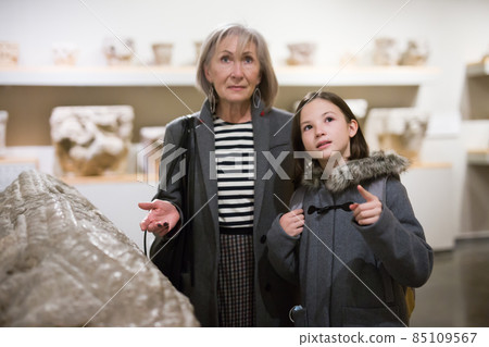 Preteen girl visiting museum of ancient sculpture her grandmother Preteen girl visiting museum of ancient sculpture her grandmother 85109567