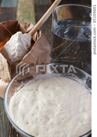 Wheat flour starter culture is ready to be added to the dough. Spoon with flour and water on the table. Front view. Wheat flour starter culture is ready to be added to the dough. Spoon with flour and water on the table. Front view. 85109801