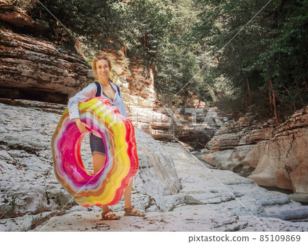 A smiling girl with a bright inflatable ring stands among the canyons in the Khosta nature reserve A smiling girl with a bright inflatable ring stands among the canyons in the Khosta nature reserve 85109869