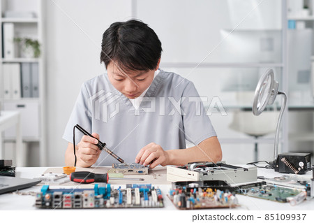 Young Chinese female technician in uniform repairing circuit board Young Chinese female technician in uniform repairing circuit board 85109937