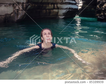 A girl swims in turquoise water in a shady gorge of canyons A girl swims in turquoise water in a shady gorge of canyons 85109939