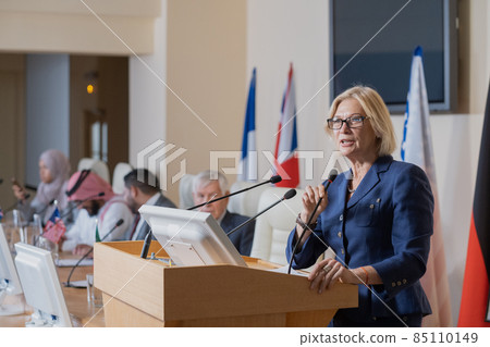 Mature female speaker in elegant suit making report Mature female speaker in elegant suit making report 85110149
