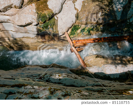 A foamy, turbulent river flows in a narrow gorge between the canyons through large logs. Top view A foamy, turbulent river flows in a narrow gorge between the canyons through large logs. Top view 85110755