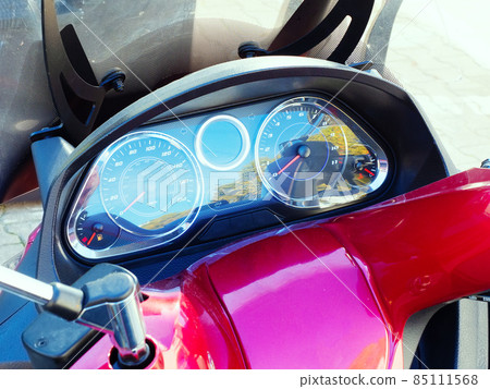 Fragment of a red motorcycle with a black speedometer. Closeup photo Fragment of a red motorcycle with a black speedometer. Closeup photo 85111568