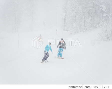 Snowboarders roll on the track in heavy snowfall and poor visibility 85111705