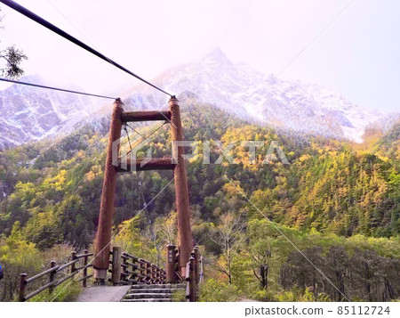 From the left bank of the Azusa River in Kamikochi, Mt. Myojin and Myojin Bridge with autumn leaves and snow makeup 85112724