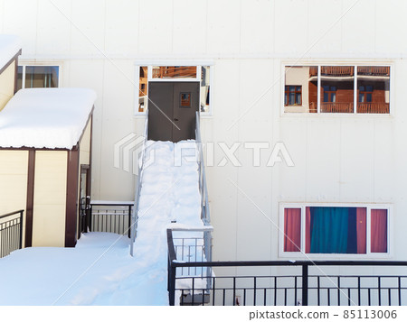 Back entrance to the building with snow-strewn steps and porch 85113006