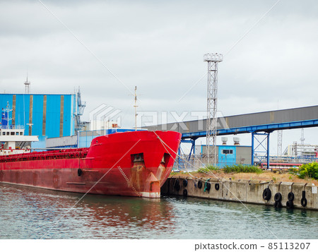 Large red industrial vessel moored to the dock with blue metal-trimmed structures Large red industrial vessel moored to the dock with blue metal-trimmed structures 85113207
