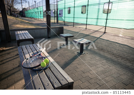 Tennis racket and ball placed on the bench on the courtside Tennis racket and ball placed on the bench on the courtside 85113445
