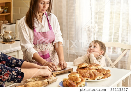 Woman kneads dough with mother and little son in kitchen 85115837