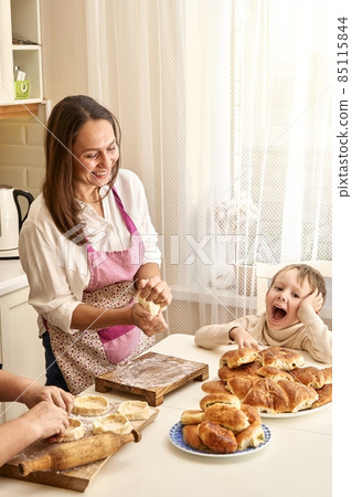 Laughing lady with senior mother and little boy cooks pies 85115844