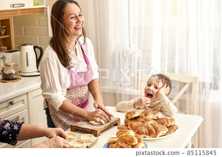 Laughing lady with senior mother and little boy cooks pies 85115845