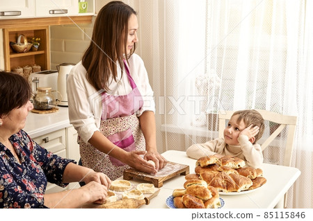 Woman kneads dough with mother and little son in kitchen 85115846