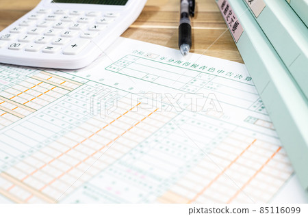 桌子上排成一排的藍色退貨單、計算器、筆和文件 85116099
