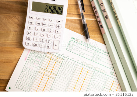 Blue return statement, calculator, pen and file lined up on the desk 85116122