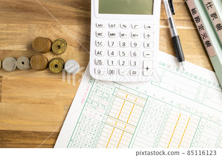 藍色歸檔財務報表、計算器、鋼筆、文件和硬幣排列在桌子上 85116123