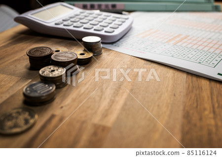藍色歸檔財務報表、計算器、鋼筆、文件和硬幣排列在桌子上 85116124